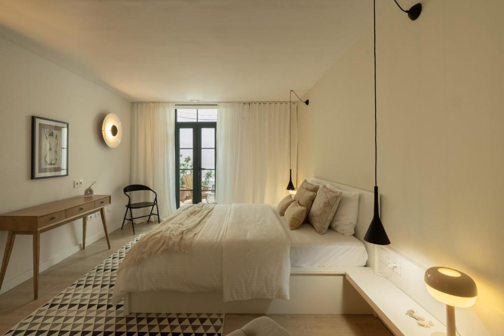 a white bedroom with a bed and a desk at Almaré in Los Llanos de Aridane