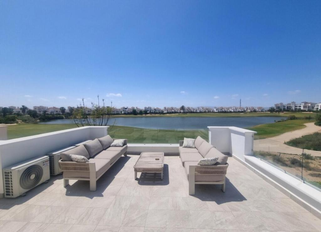 a patio with couches and a television on a roof at Beautiful views lake golf house in Roldán