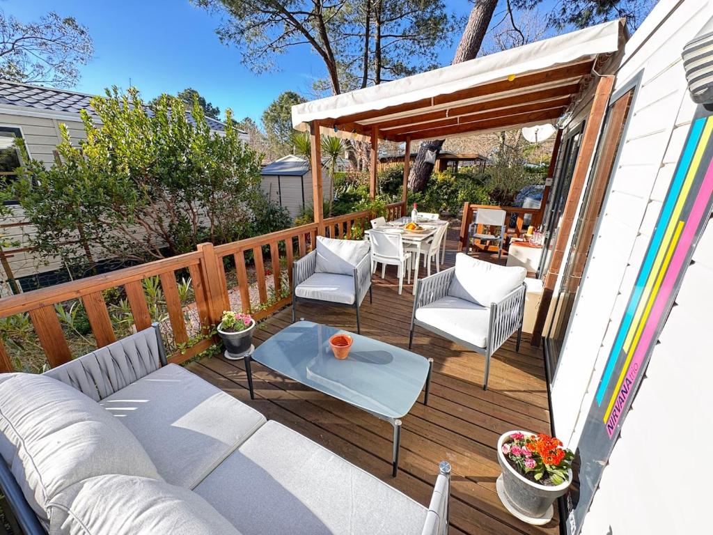une terrasse avec un canapé, des chaises et une table dans l'établissement Sous les pins du Bassin - Mobile Home avec jardin, à La Teste-de-Buch