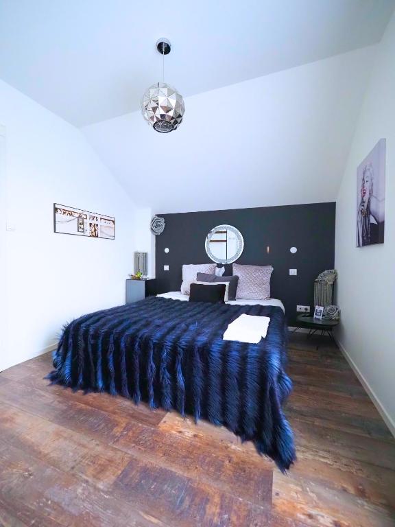 a bedroom with a large bed with a blue blanket at La Marilyn by Leslodgespa - Confort haut de gamme, salle de bain privée, jardin et cuisine commune, à 5 minutes de l'aéroport in Blotzheim