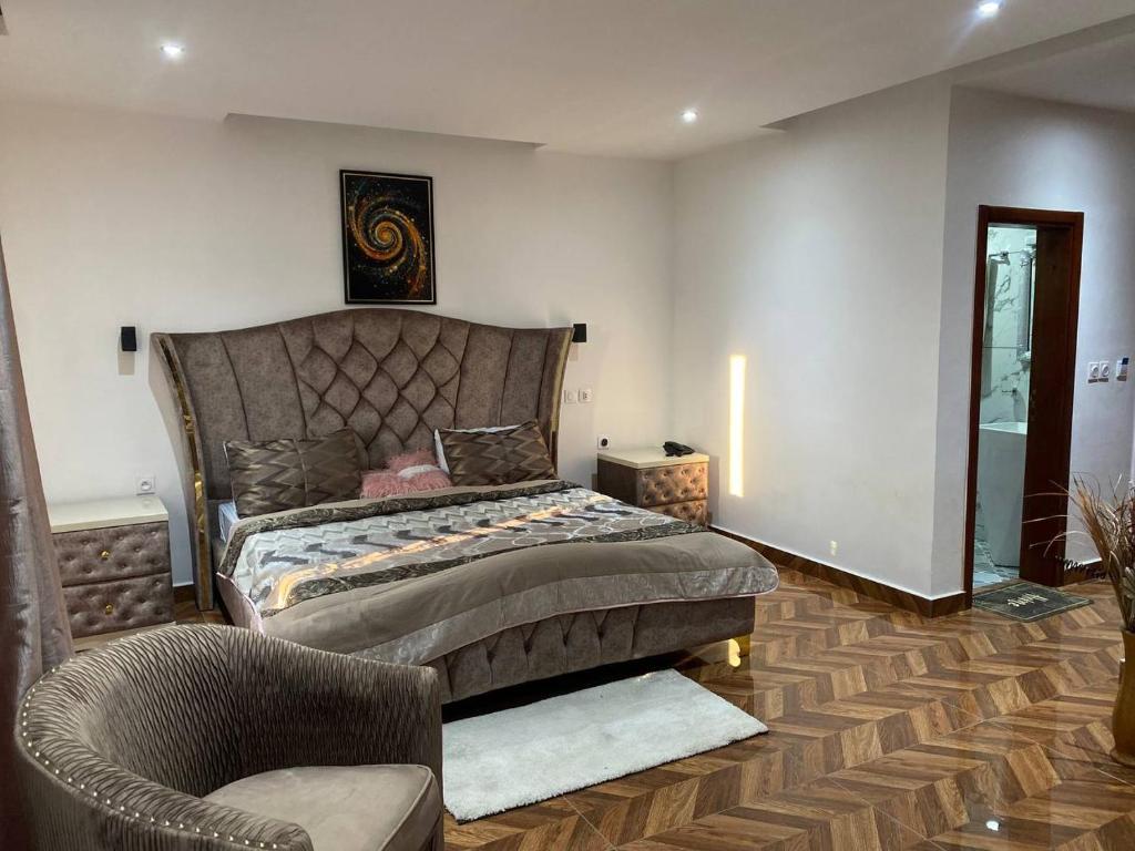 ein Schlafzimmer mit einem großen Bett und einem Stuhl in der Unterkunft FAMY Hotel in Douala