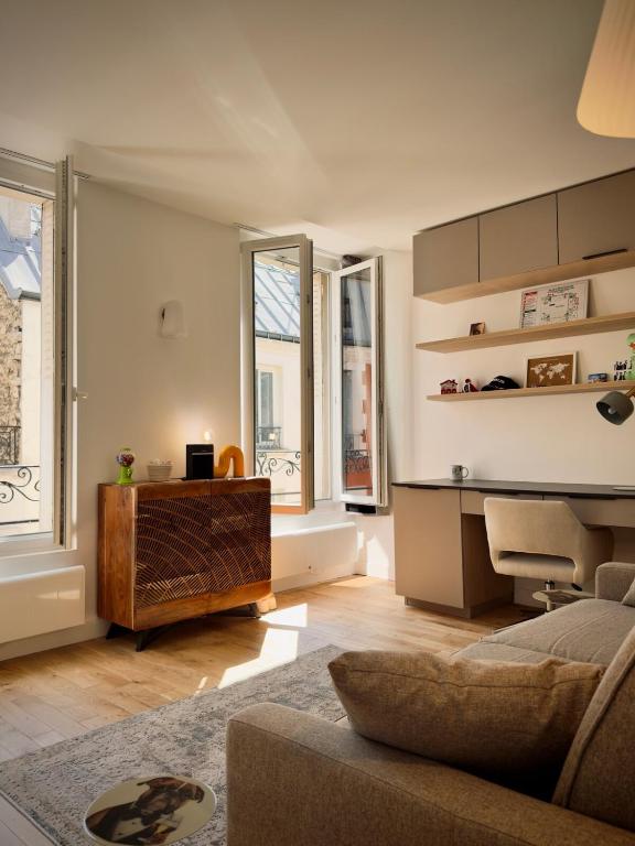 un salon avec un canapé et quelques fenêtres dans l'établissement Studio cosy et calme Paris 17 Batignolles, à Paris