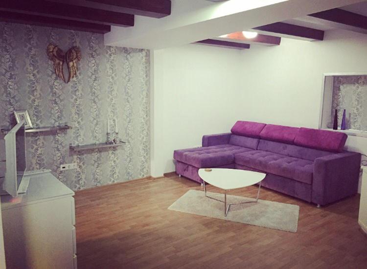 シビウにあるApartament Central Mumaの紫色のソファとテーブル付きのリビングルーム