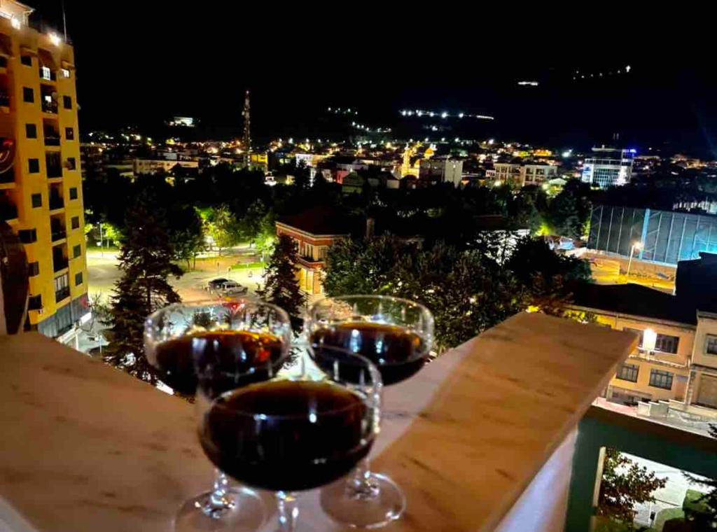 three glasses of wine sitting on a table with a view at Dukas apartment in Korçë