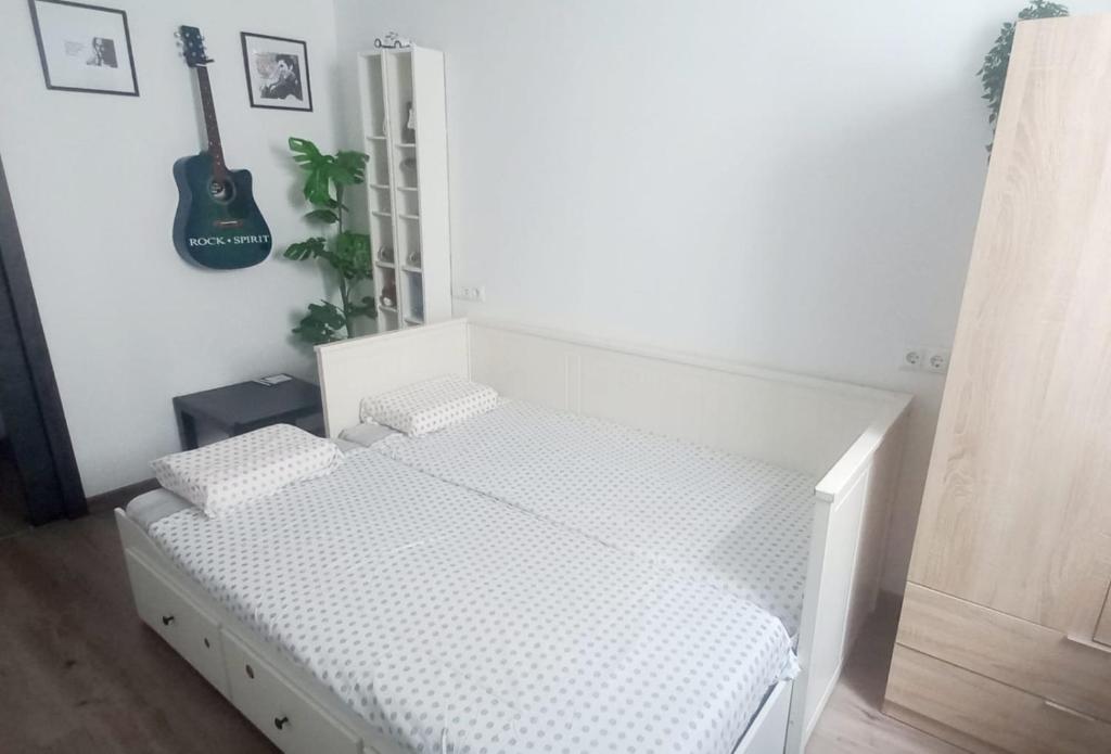 拉拉古纳Natur Vida Home Tenerife的一间白色的卧室，墙上挂着一张床和一把吉他
