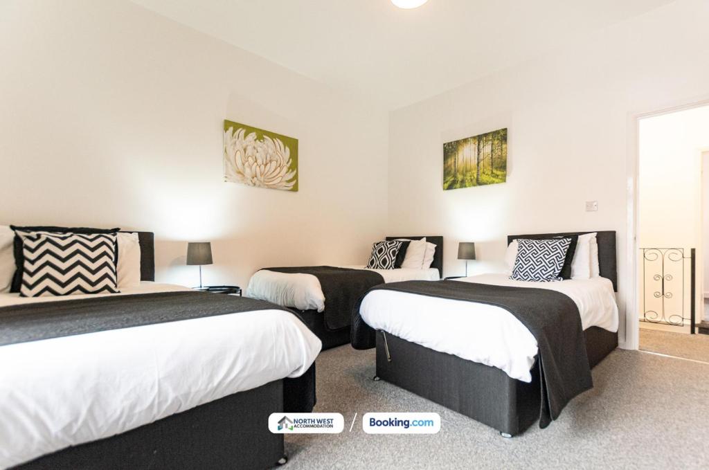 a group of three beds in a room at Cosy 2BR House in Bolton with Free WiFi & Parking in Bolton