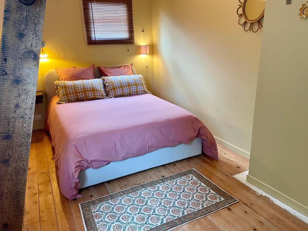 - une chambre avec un lit avec des draps roses et une fenêtre dans l'établissement La Kalinka Maison réconfortante au calme et proche du centre, à Saint-Brieuc