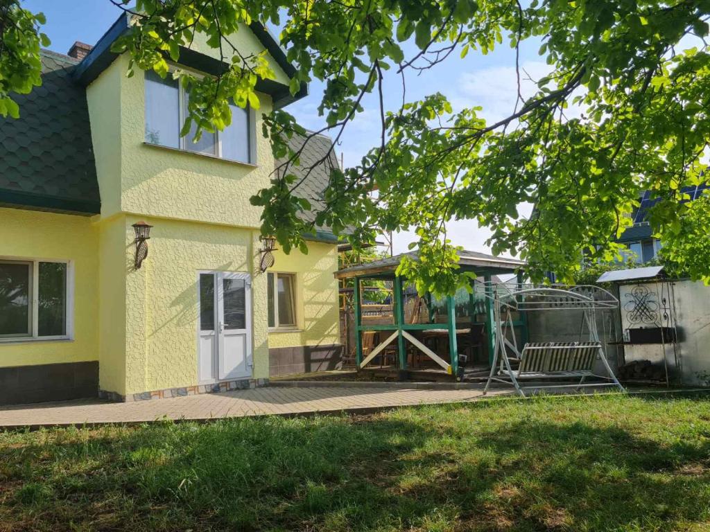 a yellow house with a gate and a swing at Fontanka Dom in Fontanka