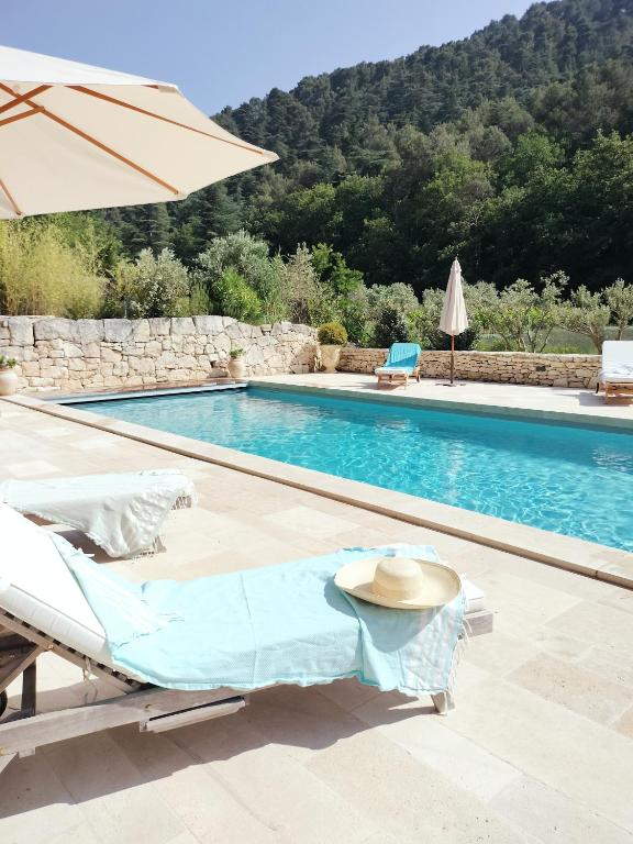 une piscine avec une table et un parasol dans l'établissement Mas du Vallon, à Oppède