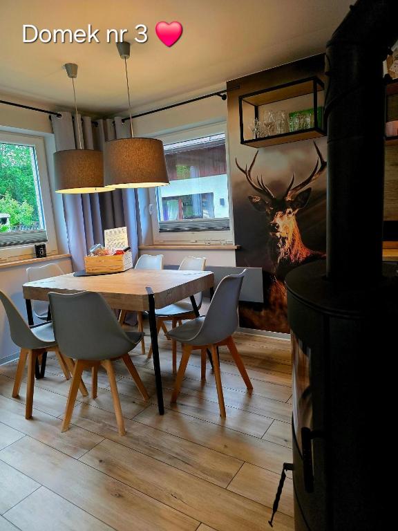 a dining room with a table and chairs and a deer painting at Zacisze Pod Śmielcem in Jagniątków