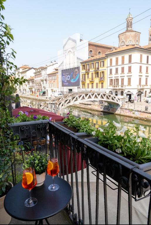 two glasses of wine on a balcony with a river at LP Apartments - Navigli View in Milan