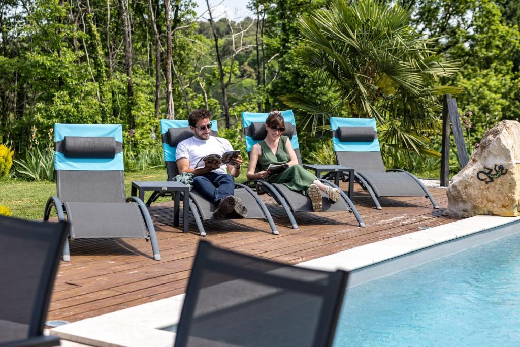 a man and woman sitting in chairs next to a swimming pool at "Notre Bastide" Maison et table d'hôtes traditionnelle et végétarienne, Piscine, jacuzzi, Clim, , à 5 mn de SARLAT in Marcillac-Saint-Quentin