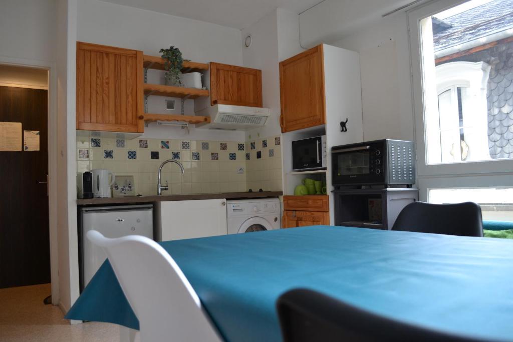 une cuisine avec une table et une table bleue dans l'établissement Plein centre - Idéal Familles 3 enfants, à Cauterets