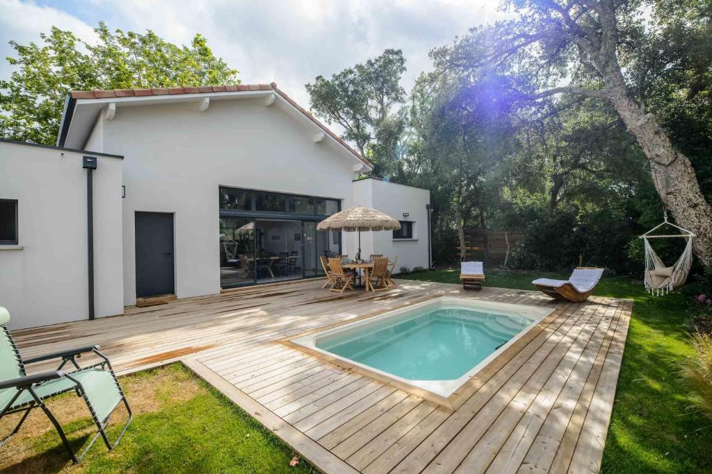 une arrière-cour avec une piscine sur une terrasse en bois dans l'établissement Superb villa with terrace and pool near the Ocean, à Moliets-et-Maa
