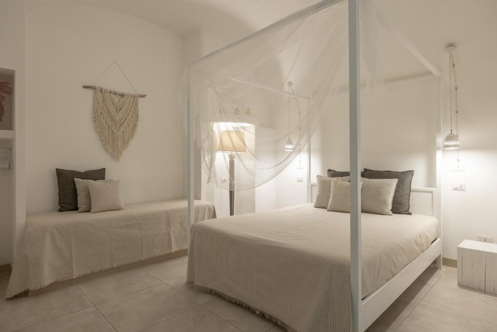 een witte slaapkamer met twee bedden en een hemelbed bij Palmieri Luxury Rooms in Gallipoli