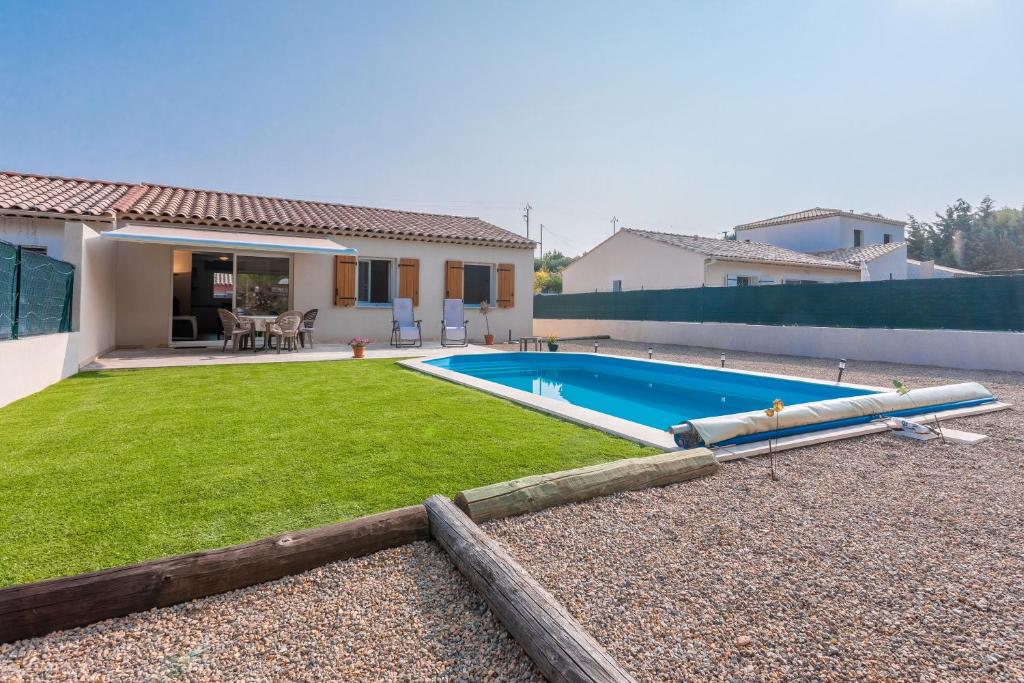 a backyard with a swimming pool and a house at Villa les coteaux du soleil in Carcès