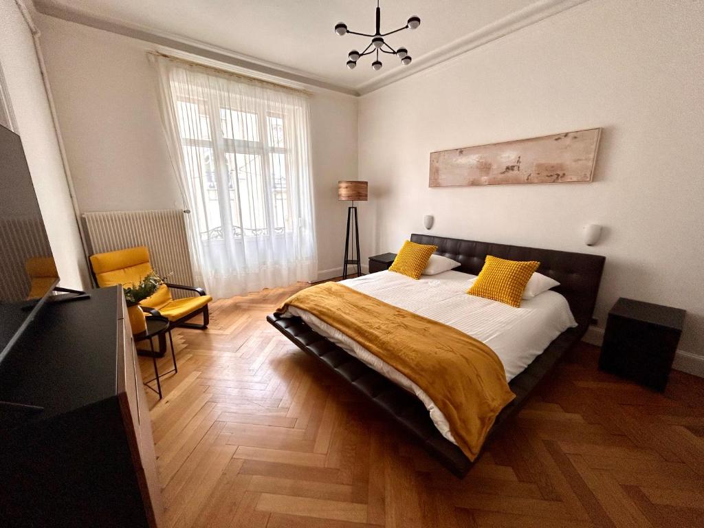 une chambre avec un grand lit avec des oreillers jaunes dans l'établissement Appartement bourgeois centre, à Strasbourg