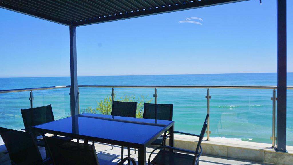 una mesa azul y sillas en un balcón con vistas al océano en Byala Cliff Sea View Suite, en Byala