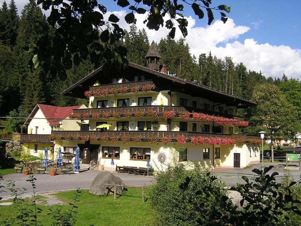 un grand bâtiment avec des fleurs sur son côté dans l'établissement Gasthof Mühle – Natur- & Wanderhotel, à Rinchnach