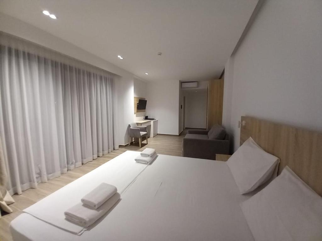 a bedroom with a large white bed and a desk at Hotel Ksamili in Ksamil