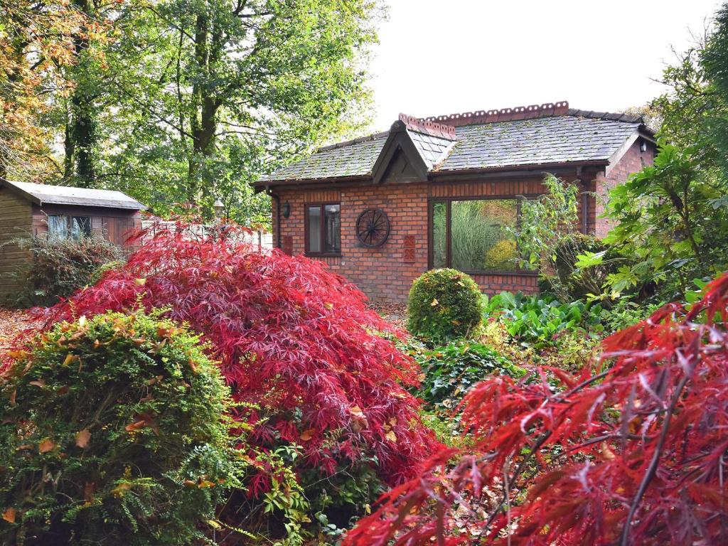 a garden with a brick house with red plants at South Lodge Cottage in Standish