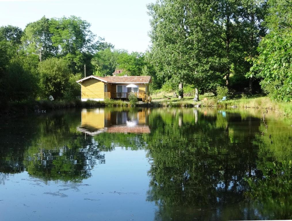 een huis aan de rivier met zijn reflectie in het water bij Chalet " Côté Lac " in Castets