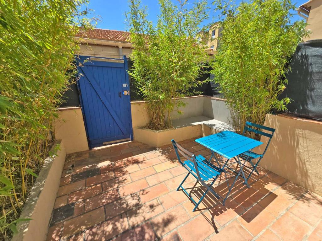 2 chaises et une table sur une terrasse avec une porte bleue dans l'établissement GregBnb - Studio 25m2 - Terasse 30m2 - CLIMATISÉ, à Toulon
