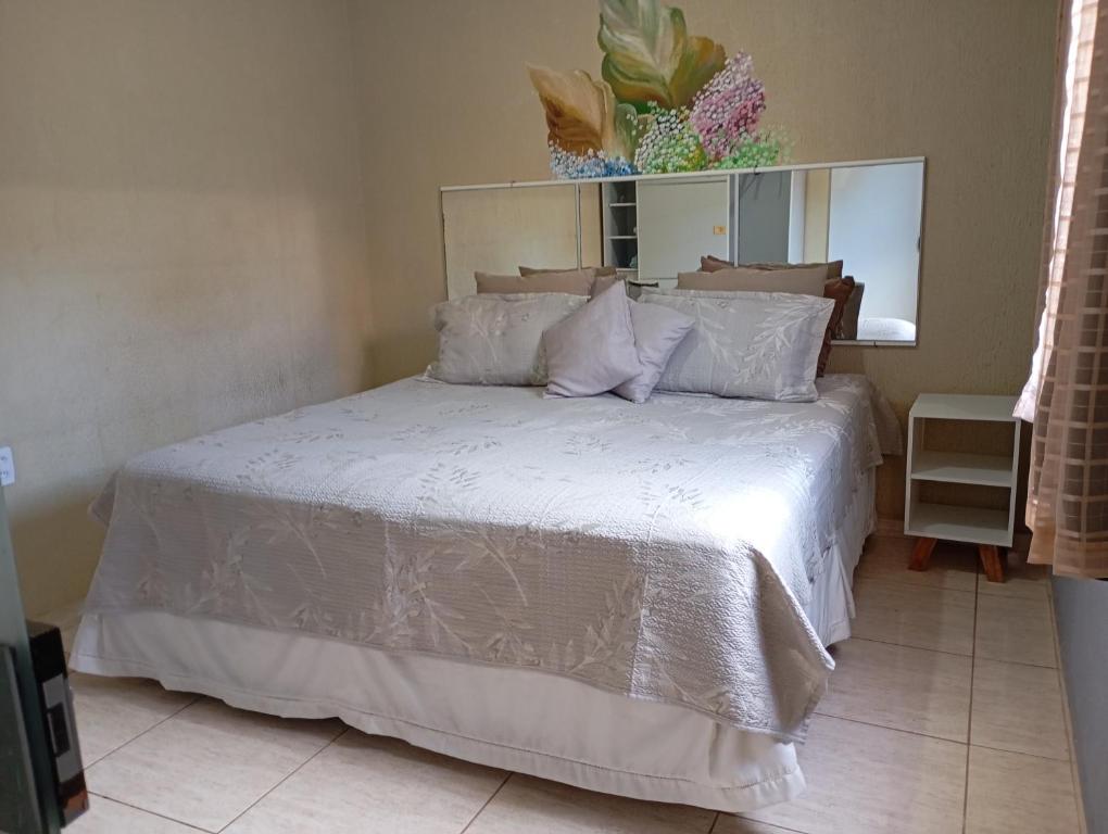 a bedroom with a bed with white sheets and a mirror at Apto 10 preço acessível in Brasília