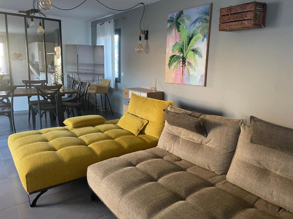 un salon avec un canapé jaune et une salle à manger dans l'établissement Villa avec piscine - mer Méditerranée sud de la France, à Torreilles