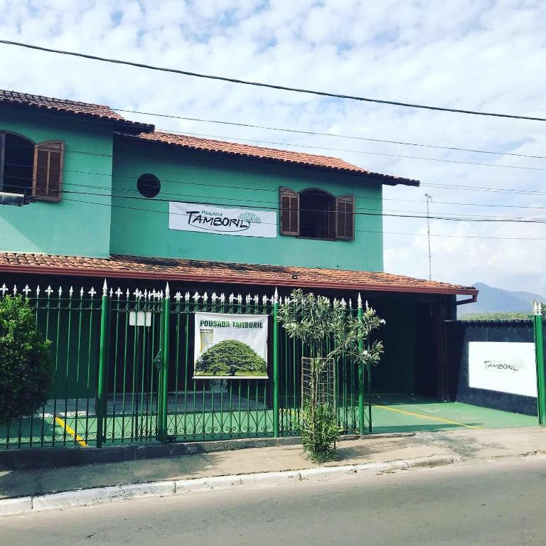 a green building with a fence in front of it at Pousada Tamboril in Brumadinho