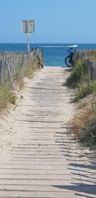 un vélo garé sur un chemin en bois près de l'océan dans l'établissement Appartement vue mer, à Marseillan