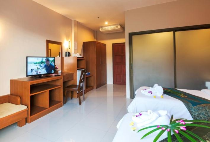 a hotel room with two beds and a television at Katanoi Resort in Kata Beach