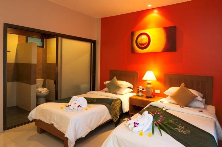 a hotel room with two beds and a red wall at Katanoi Resort in Kata Beach
