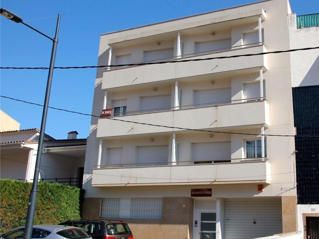 un edificio de apartamentos blanco con coches estacionados frente a él en Estartit Park 1-1, en Torroella de Montgrí