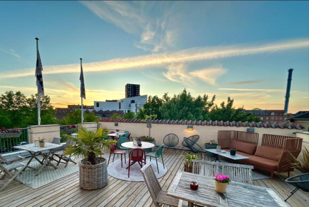 Un patio con mesas y sillas en un tejado. en City Hotel Nattergalen, en Odense