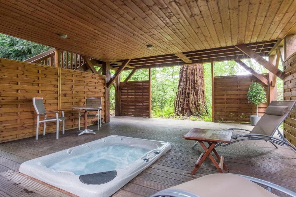 a jacuzzi tub on a deck with a table and chairs at Manoir Du Parc (Adults only) in Amboise