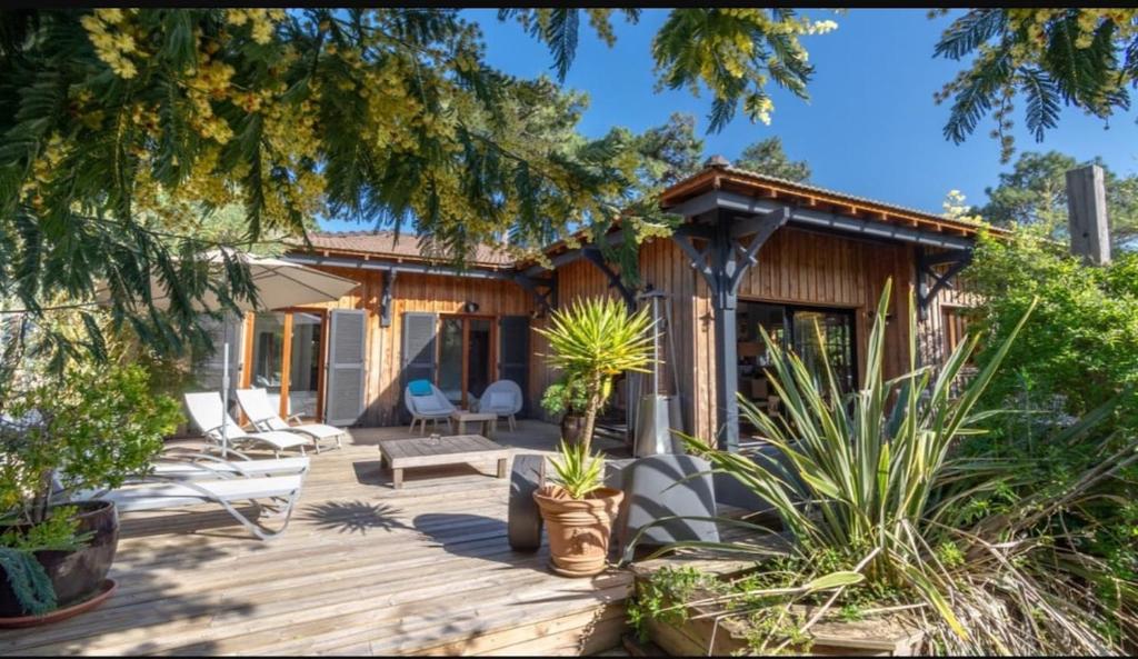 une terrasse en bois avec des chaises et une maison dans l'établissement Villa au cœur du Cap Ferret, à Lège-Cap-Ferret