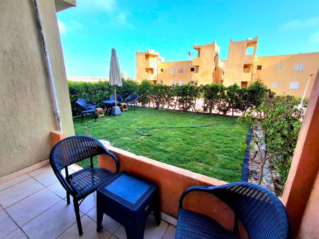 einen Balkon mit Stühlen und einen Garten mit Rasen in der Unterkunft Doblex Beach Chalet with Private Garden in Reem ElFala Resort in El-Alamein