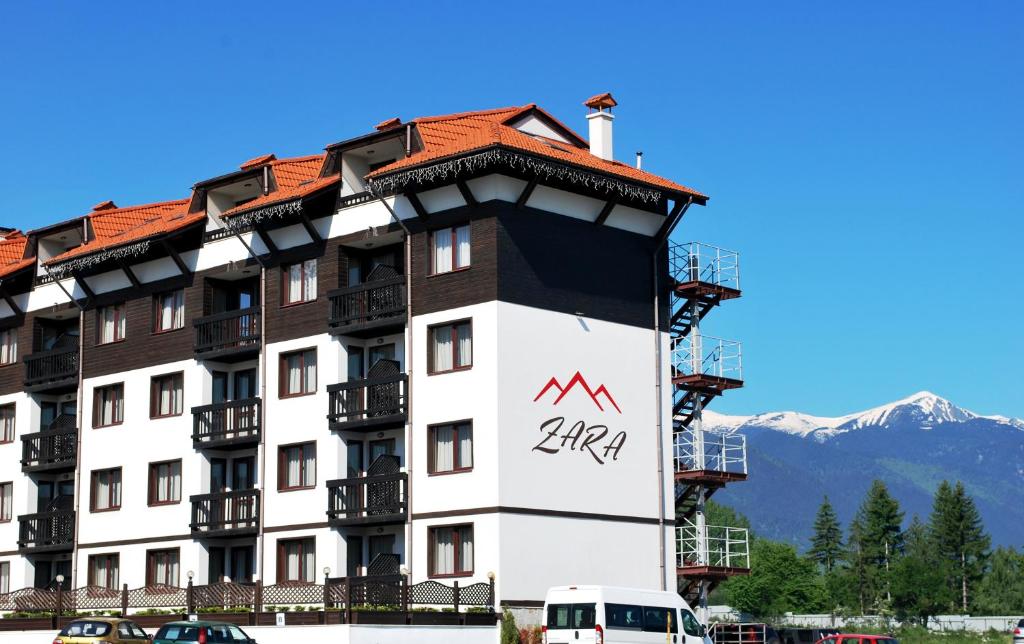 a large white building with a red roof at Zara Hotel in Bansko