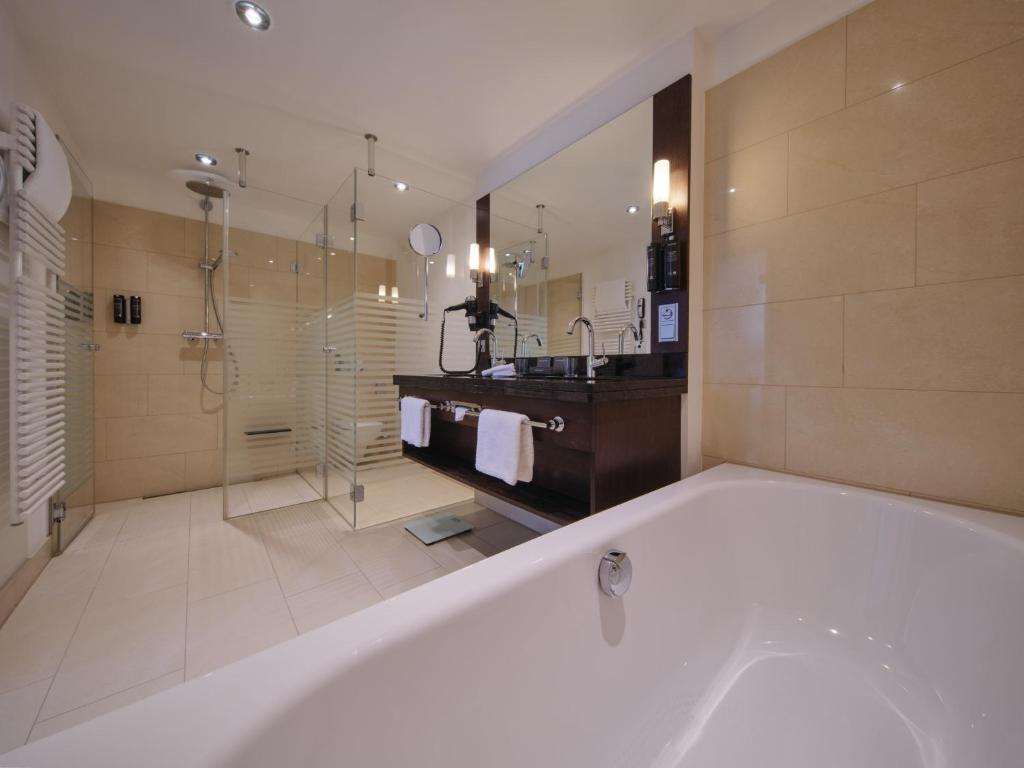 a large bathroom with a tub and a sink at Steigenberger Graf Zeppelin in Stuttgart