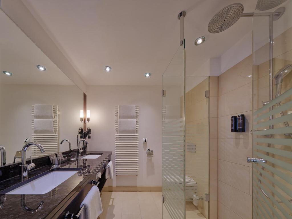 a bathroom with two sinks and a shower at Steigenberger Graf Zeppelin in Stuttgart