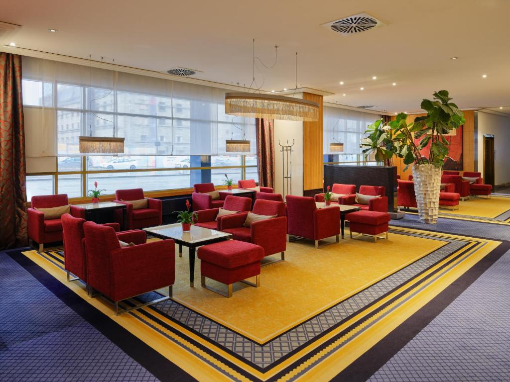 a lobby of a hotel with red chairs and tables at Steigenberger Graf Zeppelin in Stuttgart