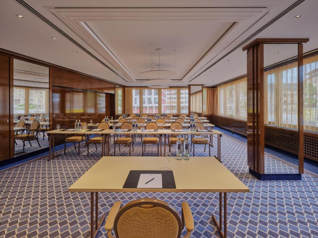 a large room with tables and chairs and windows at Steigenberger Graf Zeppelin in Stuttgart