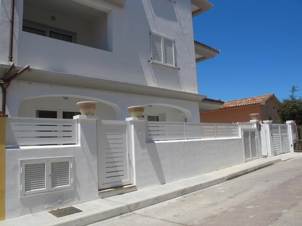 een wit huis met witte luiken en een hek bij Guest House Suite in Olbia