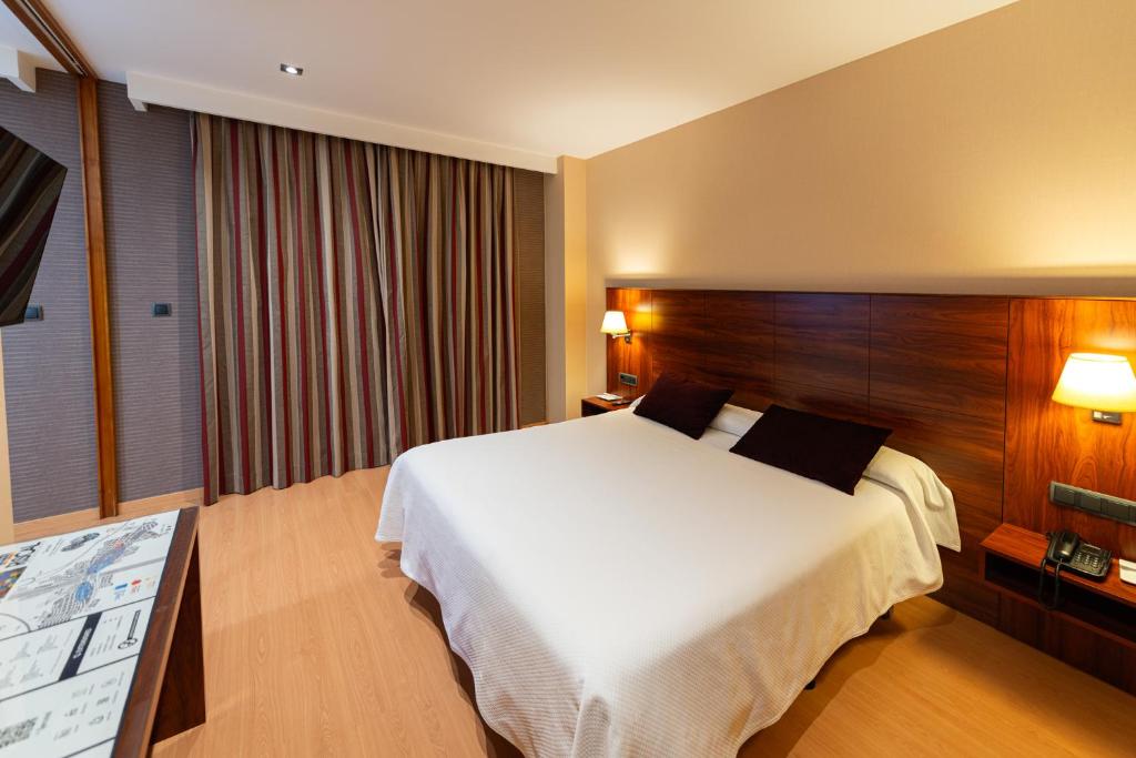 a hotel room with a large bed and a table at Sercotel Riscal in Puerto Lumbreras
