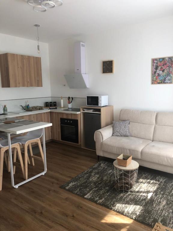 a living room with a white couch and a kitchen at Casa Armando, beau F2, 2 places de parking clos, proche Disneyland in Quincy-Voisins