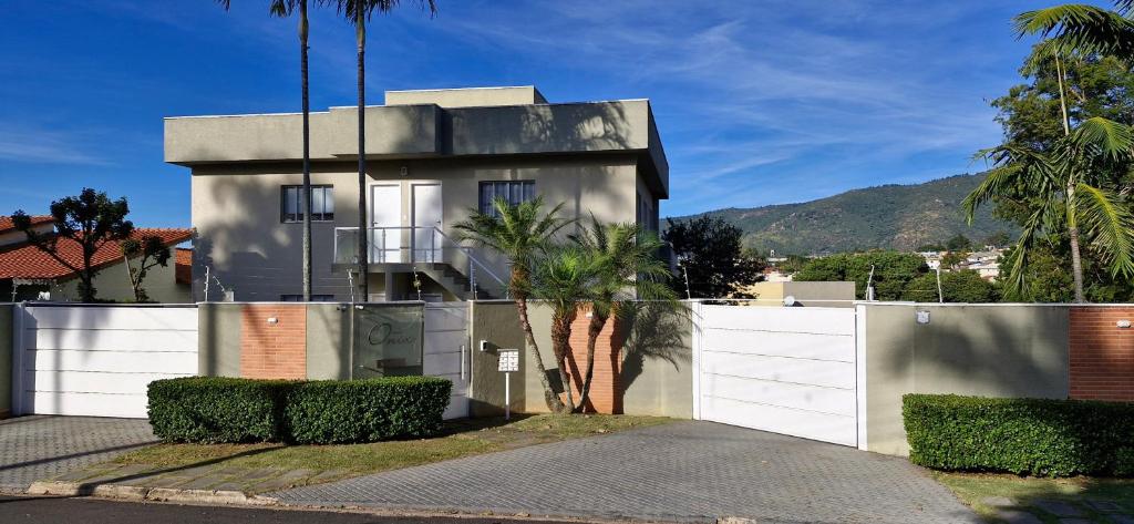 a house with a white fence and palm trees at Apto Inteiro em Atibaia do lado da Av Lucas Bairro Nobre in Atibaia
