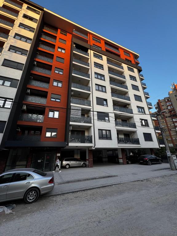 Un gran edificio de apartamentos con un coche aparcado delante. en Apartman Crystal Centar, en Novi Pazar