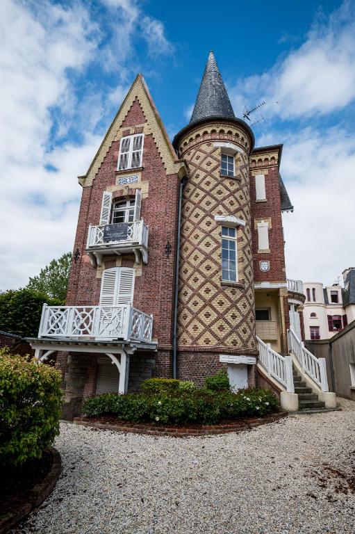un grand bâtiment en briques avec une tour dans l'établissement DUPLEX villa ancienne, 59 m2 , vue mer et plein centre!, à Villers-sur-Mer
