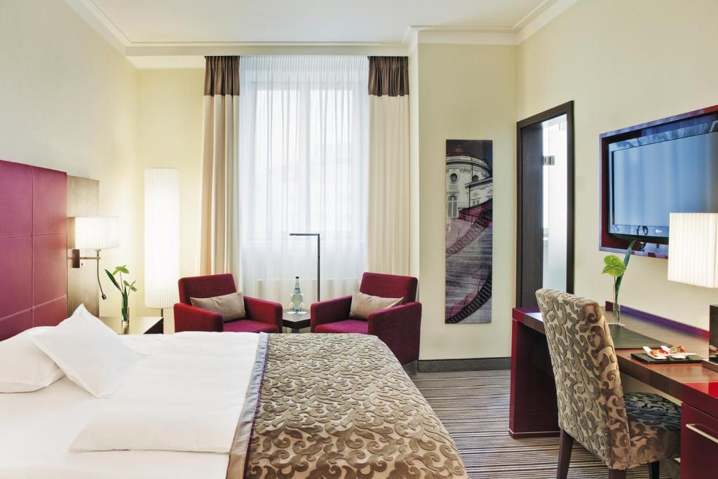 a hotel room with a bed and a desk and chairs at Steigenberger Graf Zeppelin in Stuttgart